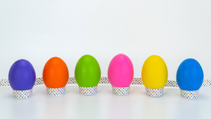 colorful eggs tied with a festive ribbon on a white wooden background.