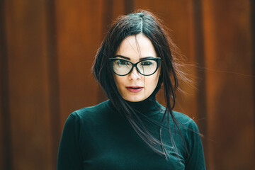 Beauty sexy fashion model woman portrait wearing eye glasses. Elegant woman looking at camera in the black dress with glasses