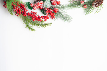 Christmas flat lay, spruce twigs, red berries and cones, sprinkled with snow, on a white background, copy space