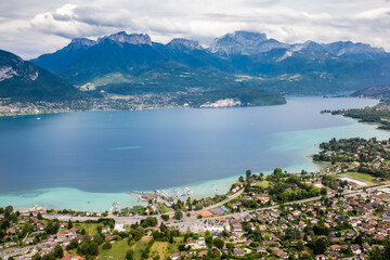 View of the Annecy lake surrounded of mountains  with cityscape in cloudy foggy weather. Rhone Alps, France.
