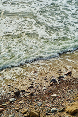 Small waves crashing on the beach with rocks