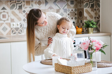 Obraz na płótnie Canvas Smiling mother takes selfie with cute daughter on tablet, happy young mom laughing makes photo with daughter at home, single mom and adopted children playing fun with phone
