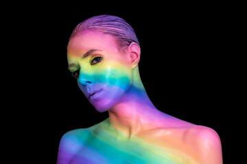 Portrait of a young woman with rainbow makeup on black background. Creative body art with colored...