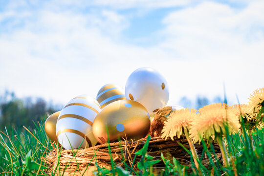 Easter egg background. Golden egg with yellow spring flowers in celebration basket on green grass. Easter decoration, foil minimalist egg design, modern design template.