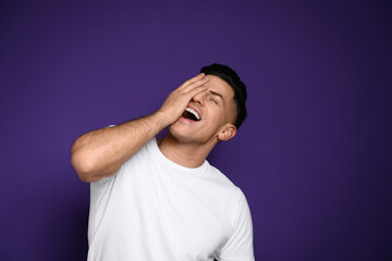 Handsome man laughing on purple background. Funny joke
