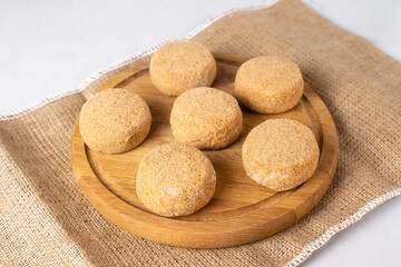 Semi-finished frozen fish cutlets in breading. Raw fish burgers on wood plate, white background. Fast cheap food, saves time in the kitchen. Hand made, lean recipe idea. 