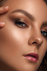 beautiful woman with delicate nude makeup and curly hair. luxury jewelry.