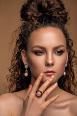 beautiful woman with delicate nude makeup and curly hair. luxury jewelry.