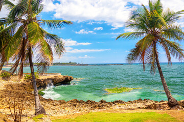 Fototapeta na wymiar Beautiful coast with palms in Santo Domingo, Dominican Republic. Caribbean sea with lighthouse.