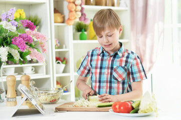boy preparing delicious fresh salad in kitchen