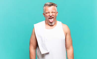 senior athlete man with cheerful, carefree, rebellious attitude, joking and sticking tongue out,...