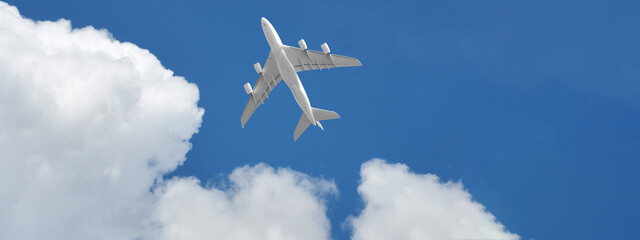 Ultra wide photo of passenger commercial airplane flying above head as shot from the ground in deep blue cloudy sky