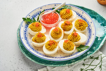 Stuffed eggs with red caviar and paprika on plate for appetizer easter table, top view, copy space. Traditional dish for Happy Easter holiday.