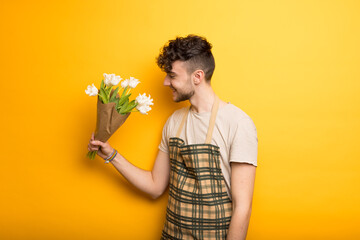 Junger Gärtner mit Blumen vor einem gelben Hintergrund