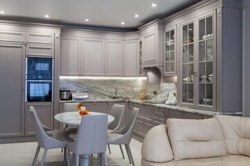 Modern beige and grey colored kitchen interior in classic style with dining table in luxury home