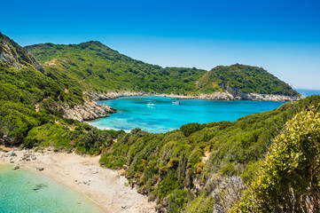 Fototapeta na wymiar Porto Timoni beach on Corfu island in Greece. Beautiful panoramic view of green mountains, clear sea water, secluded Pirates bay and empty stony beach. Famous destination for summer vacation