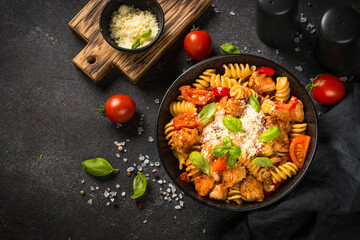Pasta chicken with vegetables on black.