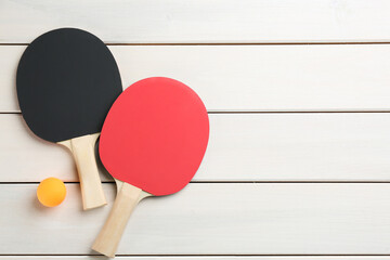 Ping pong rackets and ball on white wooden table, flat lay. Space for text