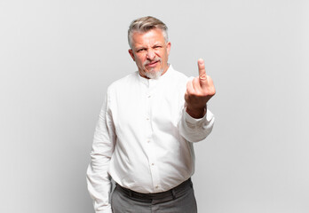 senior businessman feeling angry, annoyed, rebellious and aggressive, flipping the middle finger,...