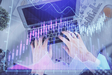 Double exposure of man's hands typing over laptop keyboard and forex chart hologram drawing. Top view. Financial markets concept.