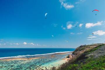 Tropical coast and blue ocean with paraglider in tropical Bali.
