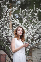 beautiful girl in a white dress walks in the garden, sakura blooming, spring bloom