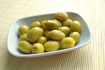 Fresh green olives and olive oil in the plate, wooden background,top view