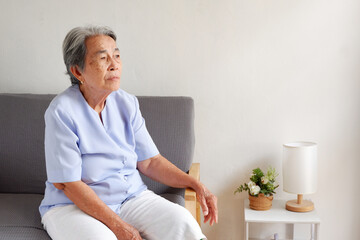 Elderly Asian woman with grey hair sitting lonely on the sofa, Aging society Sad and lonely...