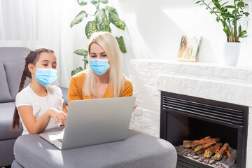 Coronavirus. Mom and daughter wearing protective mask in quarantine. Stay at home, woman working on laptop while taking care of baby. Freelance work. Child make noise, playing and disturb mom