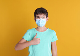 Boy wearing protective mask on yellow background, space for text. Child safety