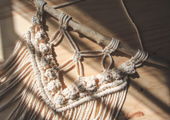 Macrame tapestry on wooden background, bohemian style