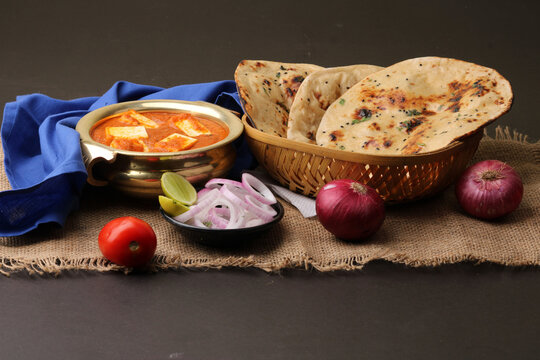 Paneer Butter Masala or Cheese Cottage Curry in serving a bowl or pan, served with naan or tandoori roti
