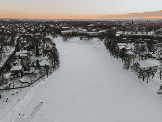 Fototapeta na wymiar Frozen lake in the city center. Agenskalns 2021 winter. People skate on the ice