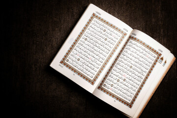 Obraz premium An open page of Quran showing Surah Al Baqarah, ayah 177 - 186 on brown background. Quran is an Islamic Holy Book 