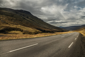 Fototapeta na wymiar a deserted asphalt road running away into the hills. Iceland. The spirit of travel and adventure. 