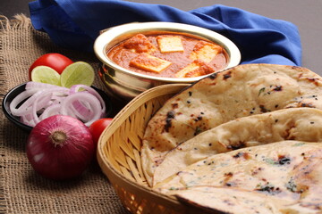 Paneer Butter Masala or Cheese Cottage Curry in serving a bowl or pan, served with naan or tandoori roti
