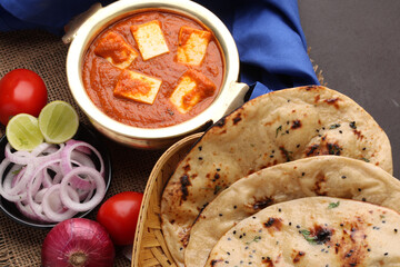 Paneer Butter Masala or Cheese Cottage Curry in serving a bowl or pan, served with naan or tandoori roti
