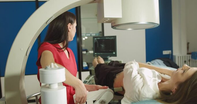 Extracorporeal shock wave therapy. Kidney stone treatment. Front view of woman doctor looking at the digital screen of the lithotriptor to determine stones position of woman patient