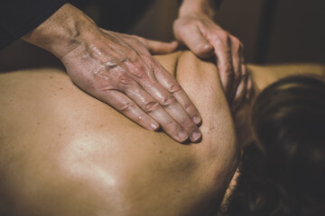 Fototapeta premium Soft focus view of man massaging a woman in a wellness center Oiled hands on a body relaxing the muscles and relieve tension .Holistic exercise for calm and clear your mind. Health well-being concept