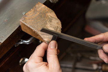 goldsmith jeweler polishes and sands a silver ring with a metal file