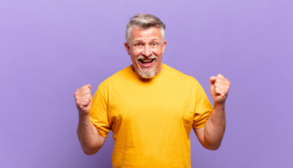 old senior man feeling shocked, excited and happy, laughing and celebrating success, saying wow!