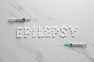 Word Epilepsy made of pills and syringes on white marble table, flat lay