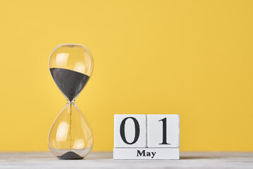 Date 1 may and hourglass on a yellow background