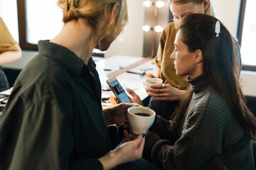 White mid woman showing her cellphone while sitting in beauty salon