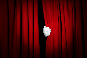 Person opening red front curtains on black background, closeup