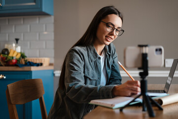 Smiling young brunette student woman studying online