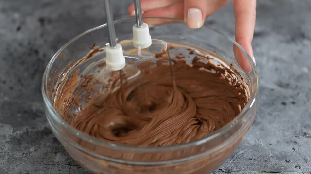 Mixing chocolate dough or batter for baking cakes, cookies, pastry. Mixer beating chocolate in bowl.
