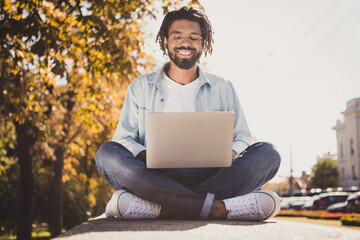 Full size photo of attractive cheerful young afro american man sit city center look laptop wear in...