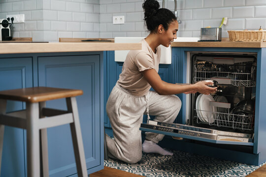 Happy Black Woman Smiling While Using Dishwasher At Home Kitchen