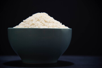 porcelain pan with raw white rice on black background